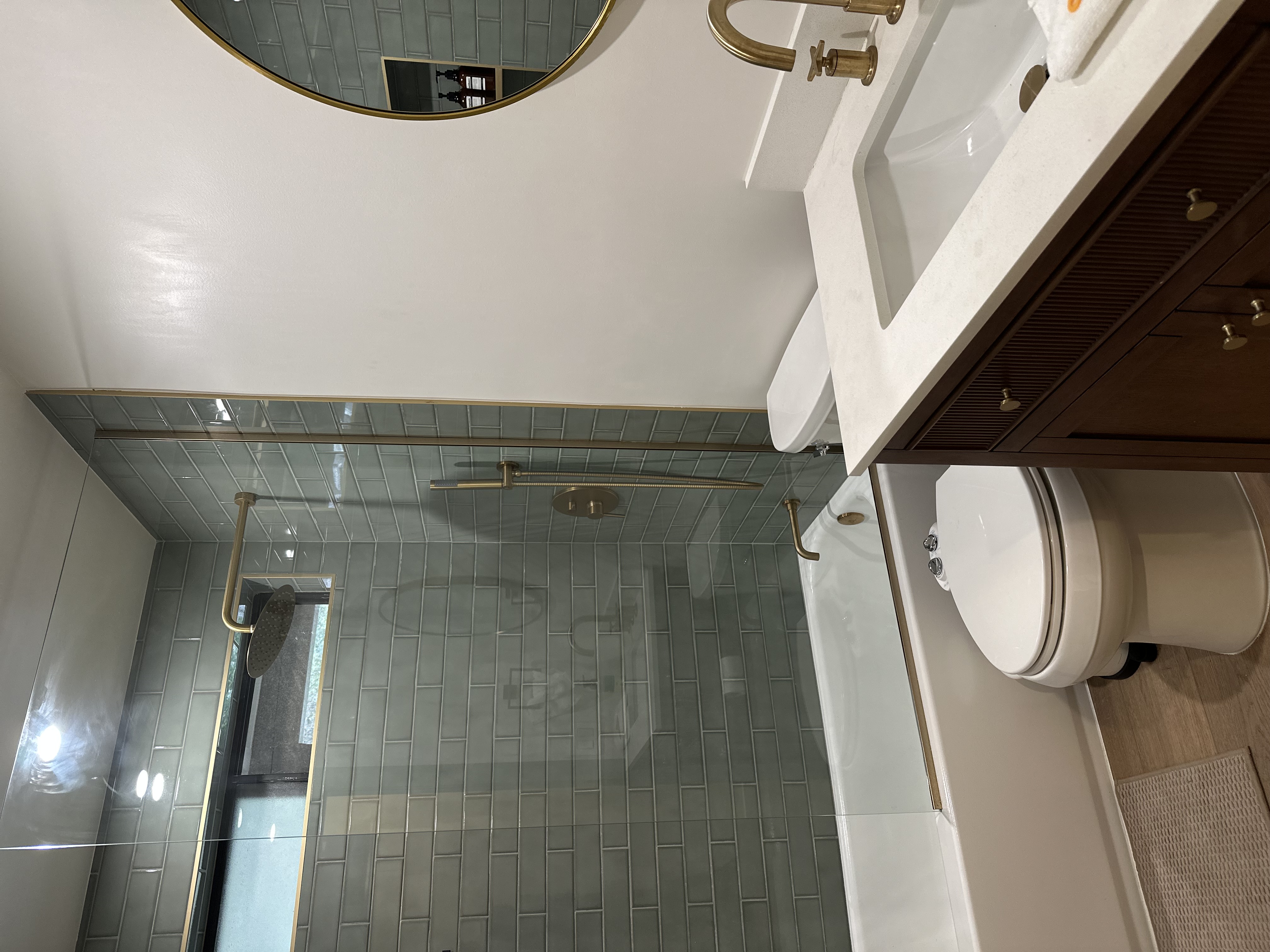 Remodeled bathroom with sage tile and brass fixtures