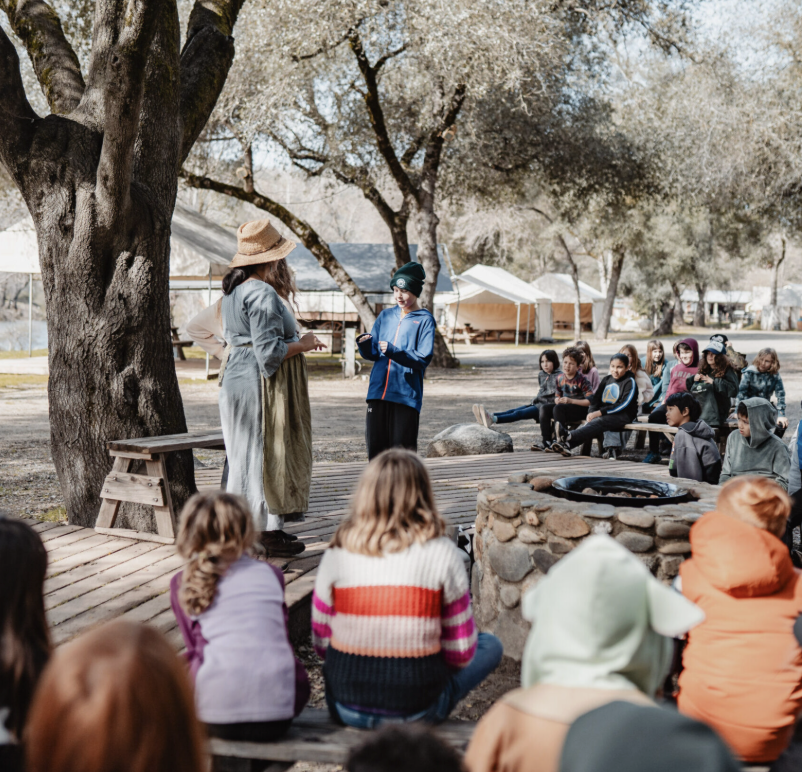 Naturalists leading a group of kids in a Gold Rush living-history skit by the campfire at Coloma Outdoor Discovery School